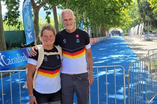 Ein weibliches und ein männliches Sportlerpaar in Shirts mit Deutschlandfarben stehen vor einer blauen Wettkampfbahn.